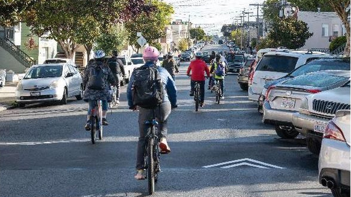 Students and adults cycling on a San Francisco neighborhood street, from SFMTA Safe School Connections board materials.