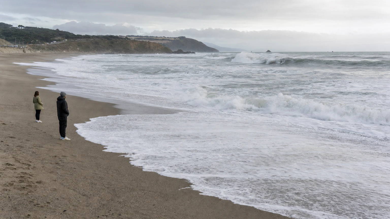 Representative editorial view of rough Pacific surf at San Francisco’s coast with people staying well back from the waterline.